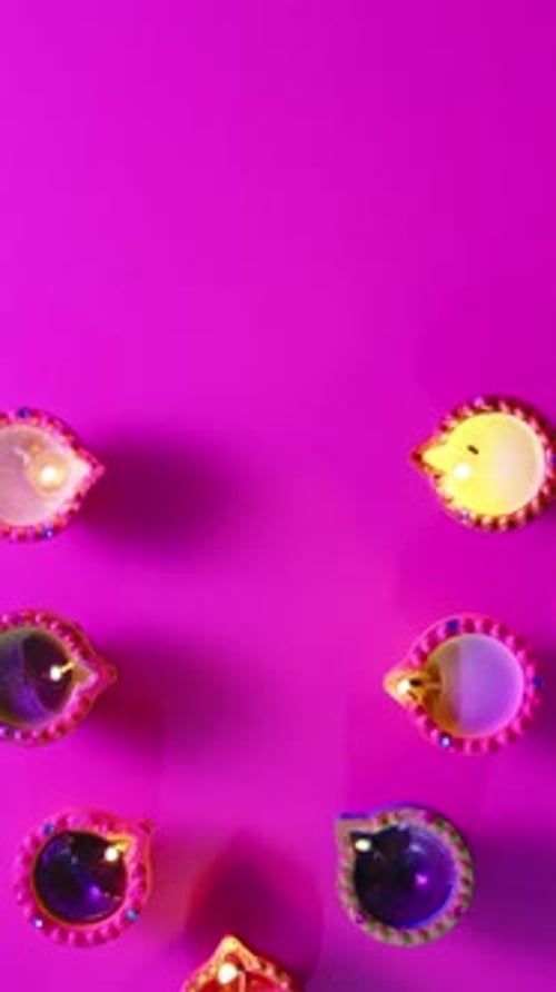 Vidéo verticale de bougies allumées en rang célébrant Diwali sur fond rose, avec espace de copie