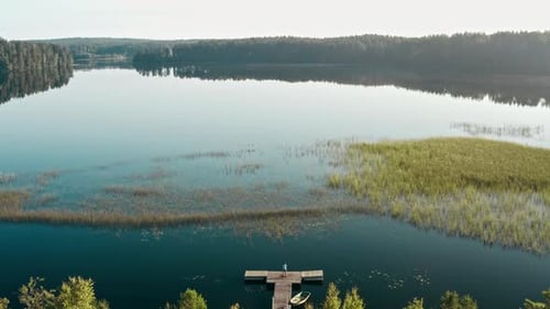 Drone Flies Over Huge Blue Lake Among Forests on a Cloudless Summer Day at Dawn