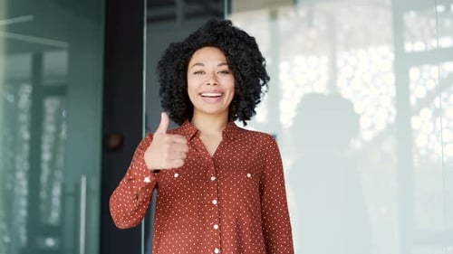 Smiling Woman Giving Thumbs Up in Modern Office