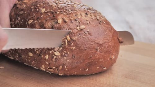 Slicing a loaf of seeded brown bread