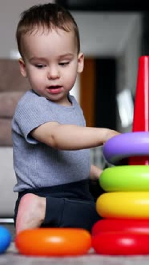 Un precioso niño caucásico construye una pirámide de juguete. Niño feliz que crece y se desarrolla.