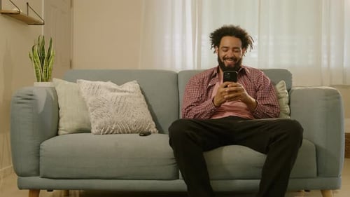 A Young Man is Relaxing on His Sofa Browsing the Internet and Connecting with Others