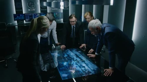 Team Discussing Technology on Interactive Table in Dark Room