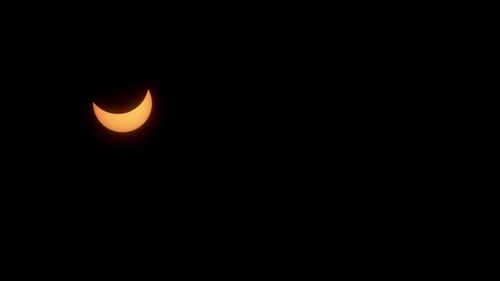 Während der partiellen Phase einer Sonnenfinsternis bewegt sich eine Halbmondsonne über den Himmel.