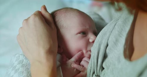 Auténtico primer plano de una madre de neo amamantando y acariciando a su bebé recién nacido en un dormitorio
