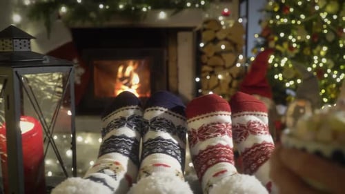 Couple Enjoying By Fireplace and Warming Up Their Feet in Woolen Socks with Christmas Tree and