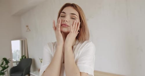 Woman Applies Touch to Face in Spa Like Setting