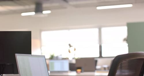 Close up of laptop on desk in sunny office, slow motion