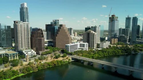Pull-out zoom aerial drone shot of Downtown Austin on a sunny day, with a revealing the city alongsi