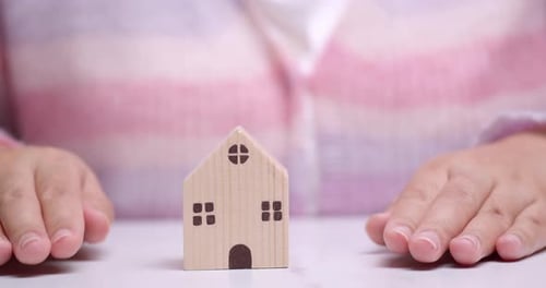 Hand covers the house. Home security concept, real estate insurance. Affordable housing. Realtor ser