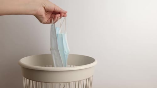 Dropping disposable face masks into trash can