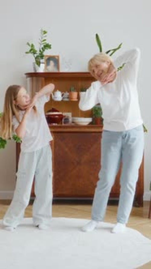 Girl and Senior Woman Enjoy Dancing Together at Home