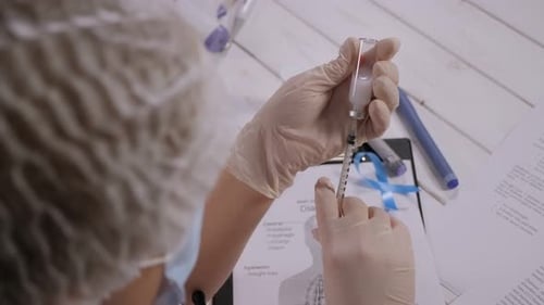 Nahaufnahme eines behandschuhten Arztes, der in einem Krankenhaus Insulin in eine Insulinspritze einnimmt