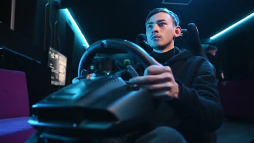 Un jeune homme joue à un jeu de course en utilisant un simulateur de conduite.