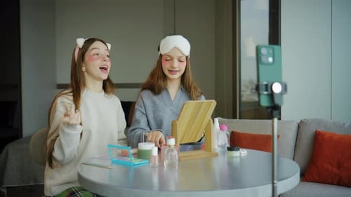 Adolescentes se preparan para un vídeo tutorial de maquillaje en una habitación bien iluminada durante la tarde mientras están sentadas