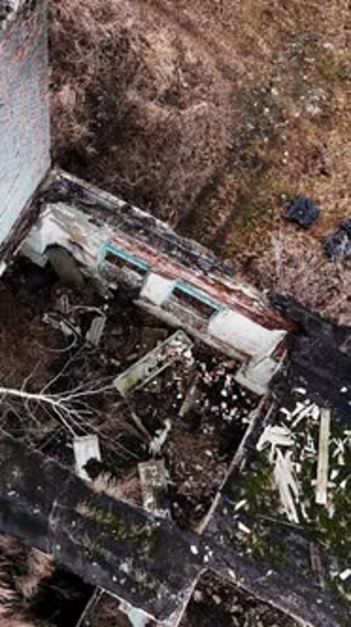 Remnants of the damaged factory building. Destroyed industrial premises overgrown with trees.