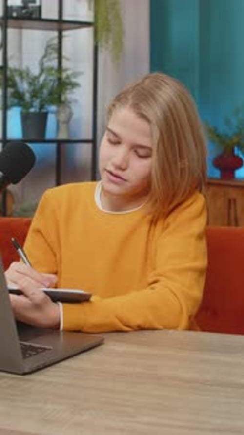 Un adolescent écrit un blog sur un ordinateur portable préparant un stream de jeu en ligne avec un microphone de studio à la maison