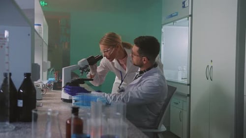 Scientists Work at Microscope in Modern Laboratory