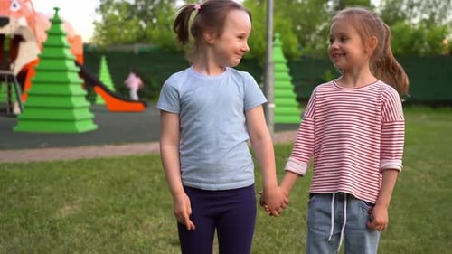 Girls Look at Camera and Laugh in Park in Summer Girlfriends on Playground