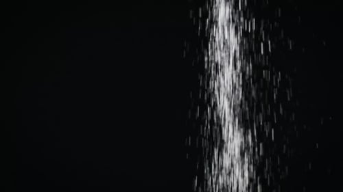 Sugar Pours in a Stream on a Black Background in Slow Motion CloseUp