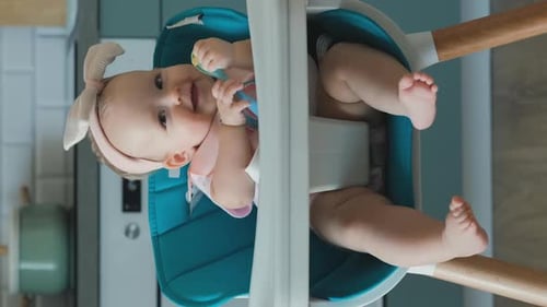 Baby Girl with Spoon Sitting in High Chair