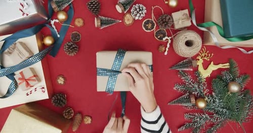 Top view of girl hands unpacking present gift box winter christmas decorations on red background.