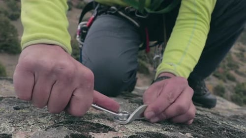 Rock climber screwing a screw to a rock before climbing. Securing a climbing training location.