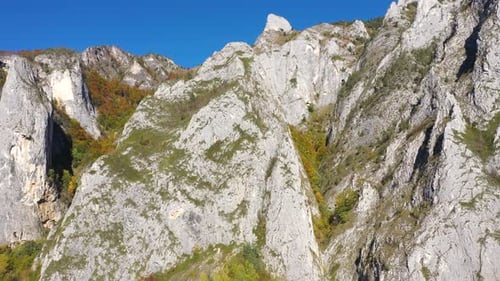 Aerial rocky alpine mountain landscape, white limestone cliffs autumn forest by drone