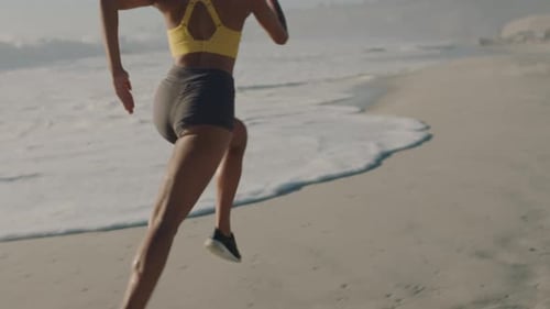 Active, fit and sporty woman running, sprinting or jogging on the seashore at the beach