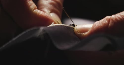 Hands Sewing Tag onto Fabric Close Up