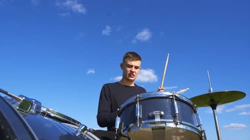 Young Adult Playing Drum Set Outdoors
