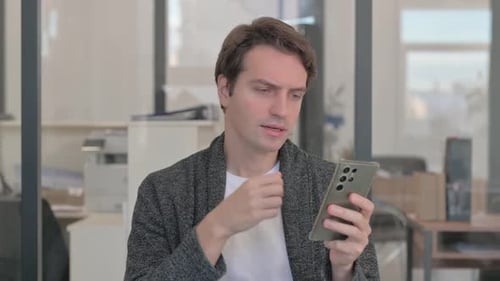 Man Celebrating Good News on Smartphone in Office
