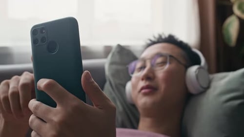 Man Relaxing on Couch Using Smartphone Indoors