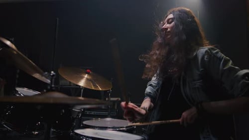 Portrait Female with Long Curly Hair Plays the Drums Girl is Rehearsing in a Studio with Drumsticks