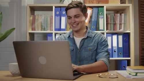 Young Adult Typing on Laptop at Desk