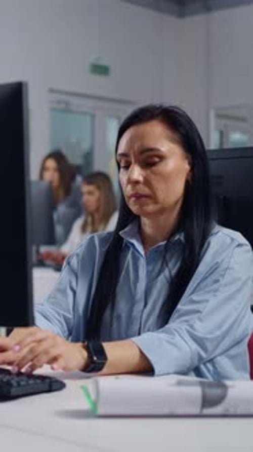 Focused Middle Aged Office Worker Typing on Computer Keyboard at Modern Workstation in Open Plan