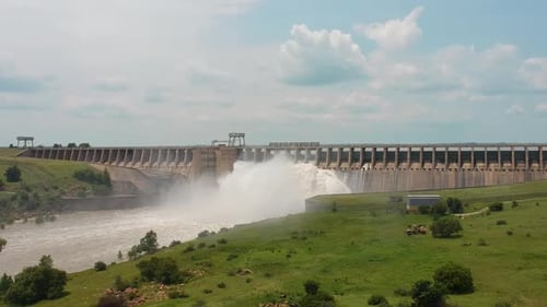 Reservoir sluice gates releasing water, long dam wall.