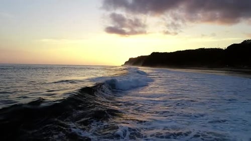 Flying Above Melasti Beach at Low Tide and Ocean Waves Rolling at Shore with Foam Aerial Evening