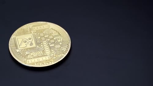 Reverse side of a golden Bitcoin cryptocurrency turning anticlockwise.