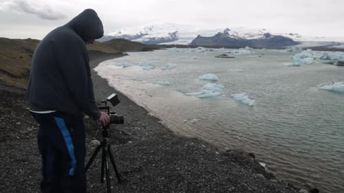Glacier Lagoon in Iceland with side view of male photographer and left to right pan.