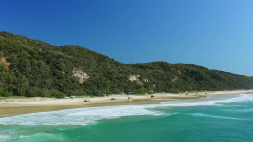 4WD Cars Driving Along Sandy Beach Shore Beside Blue Ocean Waves In Australia, 4K Aerial Drone