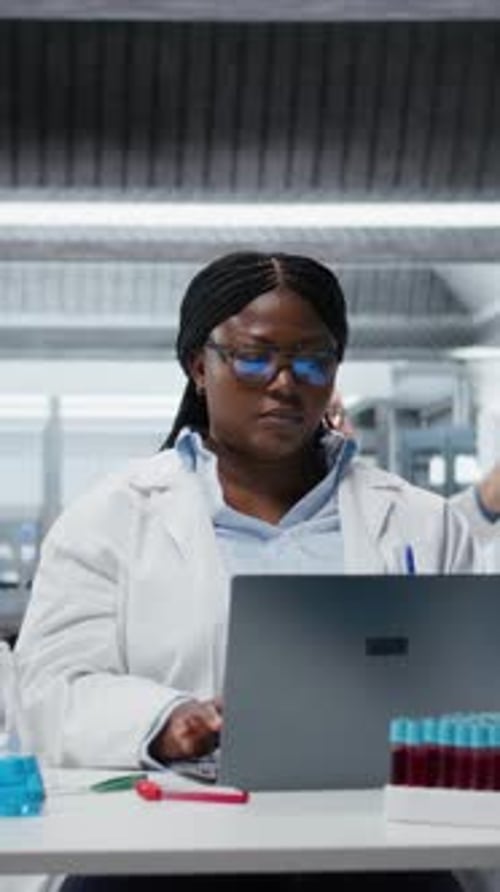 Portrait vidéo vertical d'un scientifique joyeux utilisant un logiciel pour ordinateur portable en laboratoire