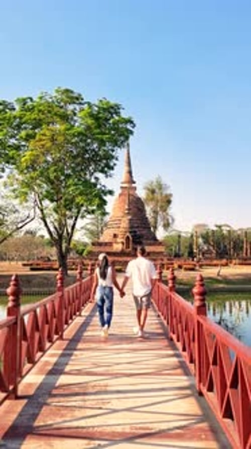 Un couple marche main dans la main sur un pont au-dessus de l'eau Sukhothaï, Thaïlande
