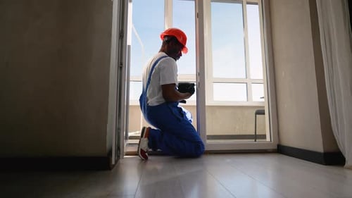 Worker Repairs Sliding Glass Door with Drill