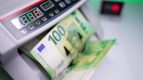 Blades of cash counting machine rotating empty. Green one hundred euro banknotes fall on the holder