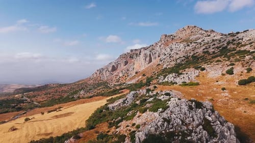 Rocky mountain slope with grasslands and clouds