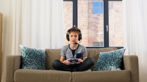 Teenager Gaming on Couch with Headset and Controller