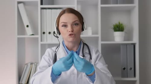 Friendly Woman Doctor in White Coat Talking on Headset