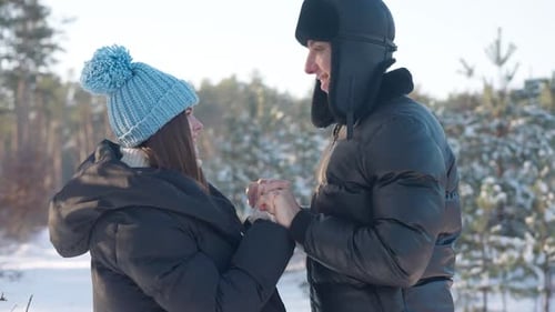 Carefree Loving Couple Looking at Each Other Holding Hands Standing in Winter Forest