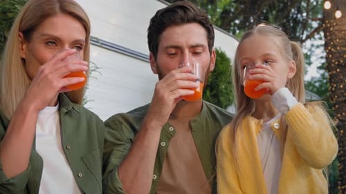 Happy Family Drinking Juice Outdoors Together